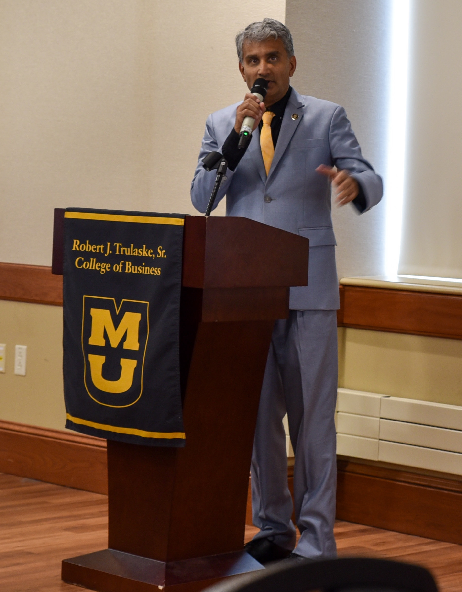 Dean Rajagopalan standing behind podium while addressing attendees at the annual Celebration of Success event
