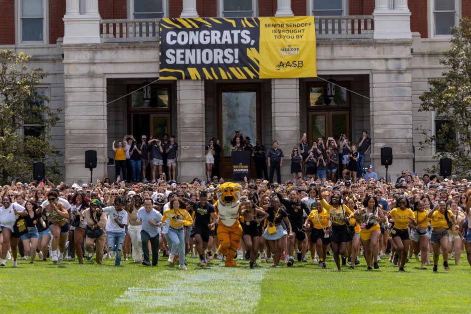 Students run in excitement across the commons after graduation