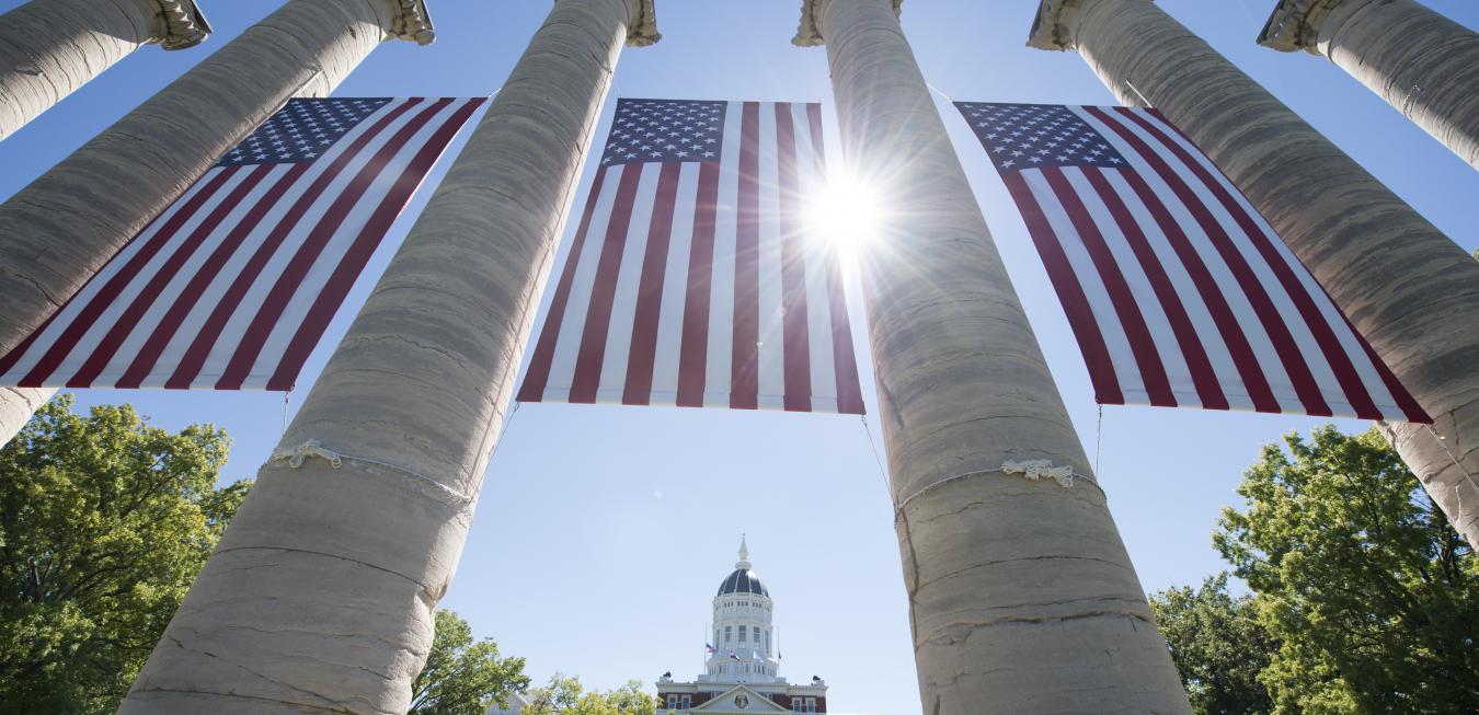 Image: Columns on the Francis Quadrangle adorned with American flags.