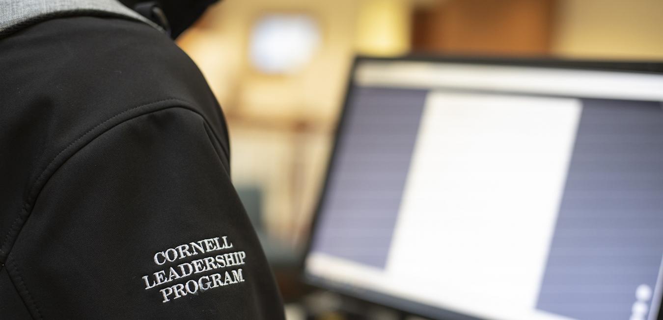 Image: Student with Cornell Leadership Program embroidered on the sleeve looking onto computer.