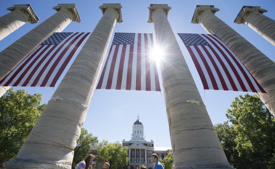 Image: Columns on the Francis Quadrangle adorned with American flags.