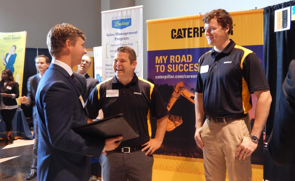 Image: Recruiters with a student at a career fair.