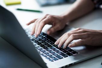 Image: Hands typing on a laptop keyboard.