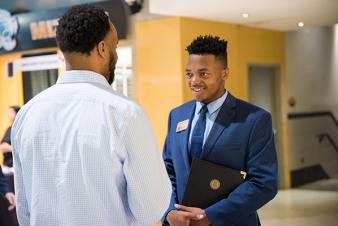 Image: Male student talking to a recruiter at a MU BCS career fair.