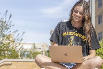 student with her laptop sitting outside