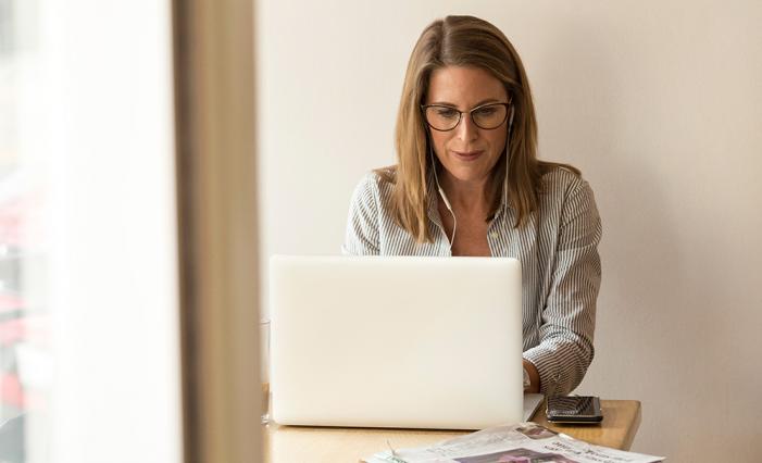 Image: Woman at a computer looking down at monitor.