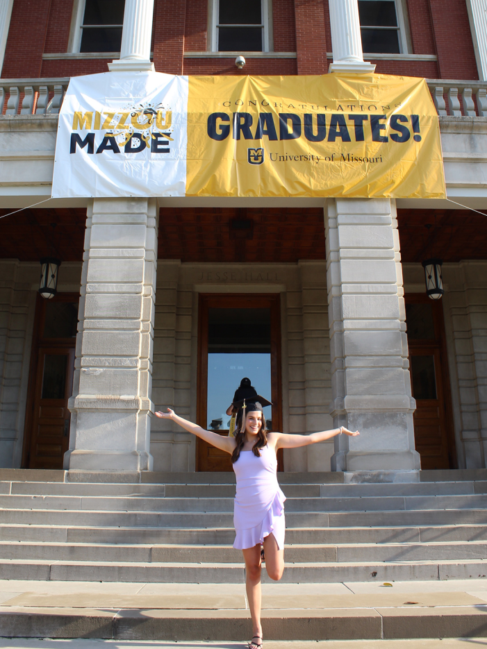 Grace Casey celebrating graduation in front of Jesse Hall